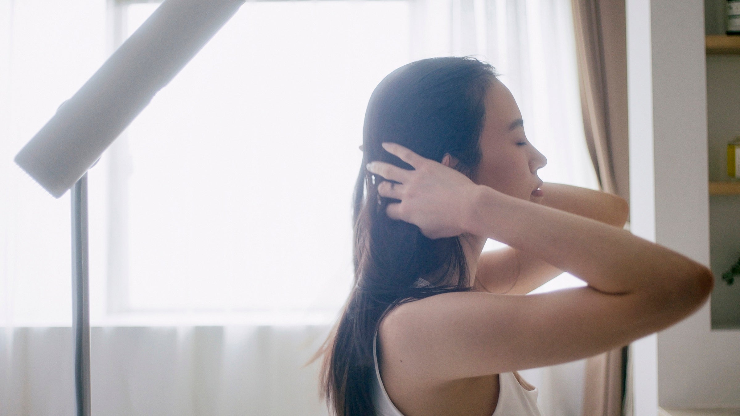 BISARAで髪を乾かしながら両手で髪を整える女性